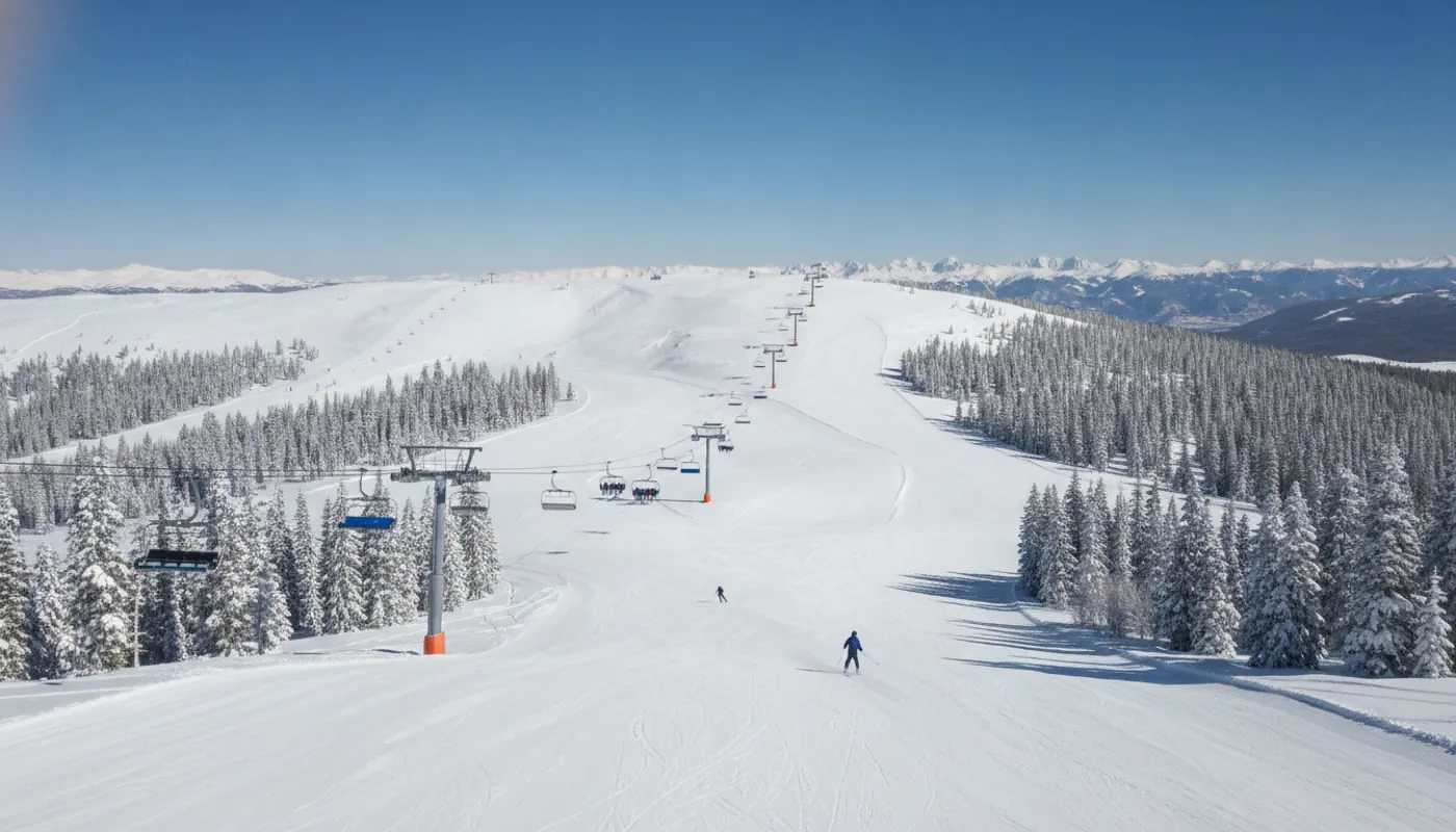 A high Colorado ski resort at midday, groomed intermediate runs winding between snow-laden pines below a broad blue-sky bowl, a modern high-speed quad rising along the ridgeline